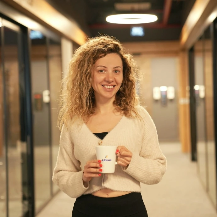 a woman holding a cup of coffee in a hallway